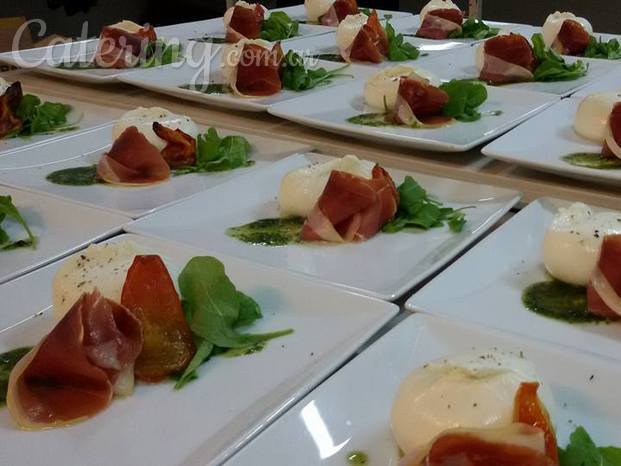 Burratina con jamon crudo, rucula, toates asados sobre pesto de albahaca